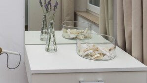 A white vanity with a mirror, two clear vases with lavender, and a glass bowl with white flowers. - Villa Providenca (Dubrovnik)