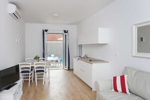 A compact living space with a kitchenette, a dining area, and a sofa.