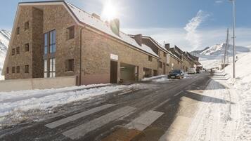Una calle cubierta de nieve con una hilera de edificios, incluyendo un hotel de fachada de piedra y ventanas grandes.
