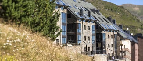 Un edificio moderno con tejado inclinado, ventanas grandes y fachada de piedra.