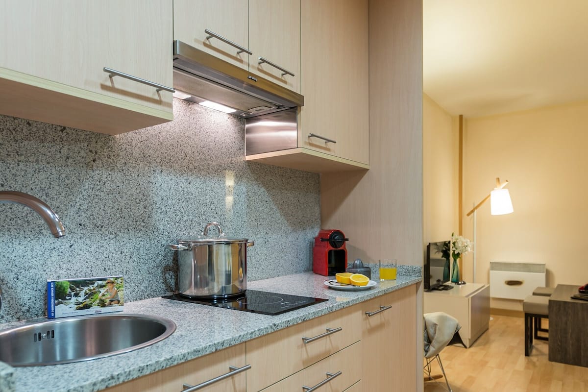 Une cuisine moderne dotée de plans de travail en granit, d’appareils électroménagers en acier inoxydable et d’armoires en bois.