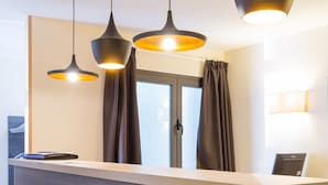 A reception desk with a wooden finish, three pendant lights, and a window with curtains.