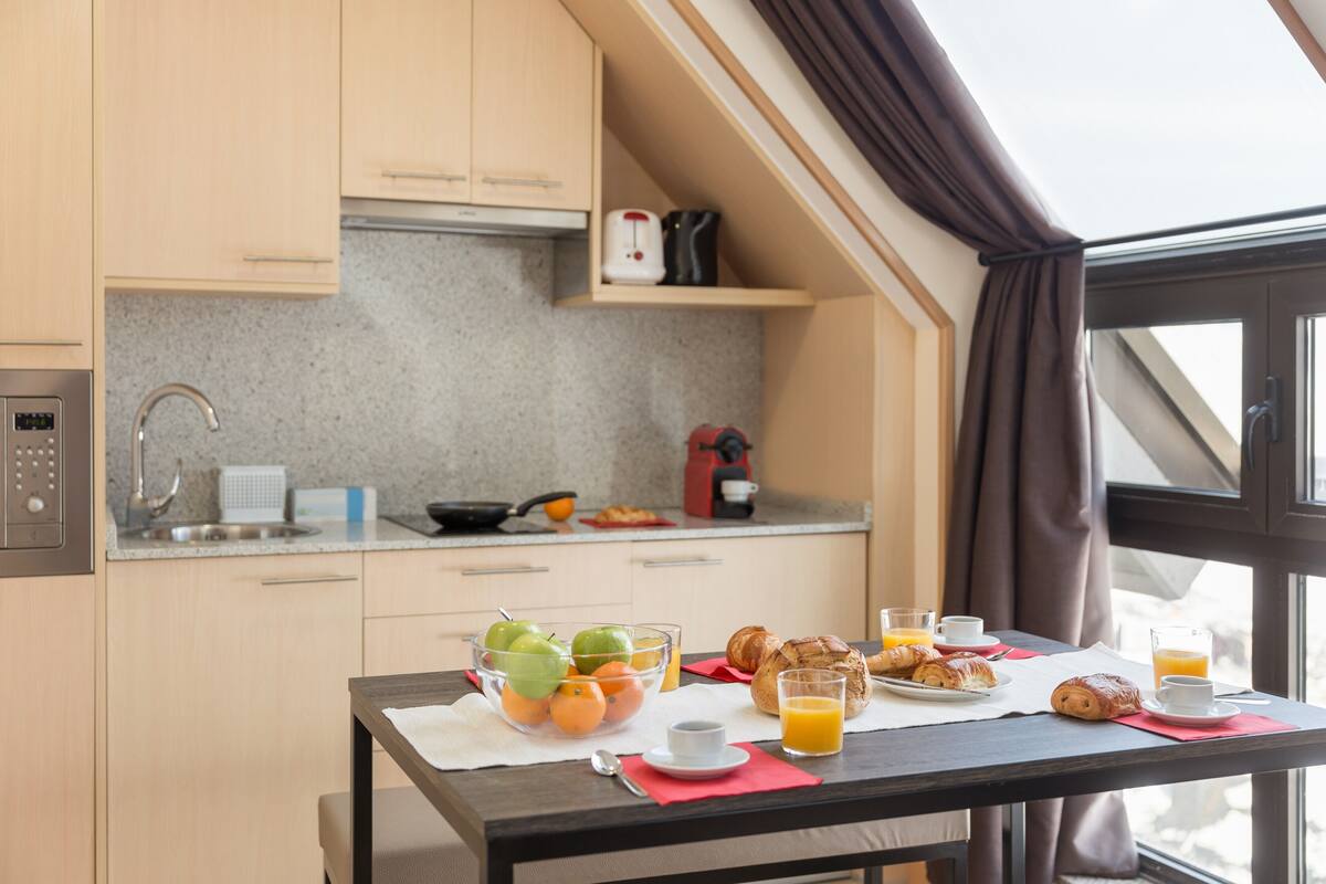Une cuisine moderne avec un coin petit-déjeuner comprenant des fruits, des viennoiseries et des boissons.