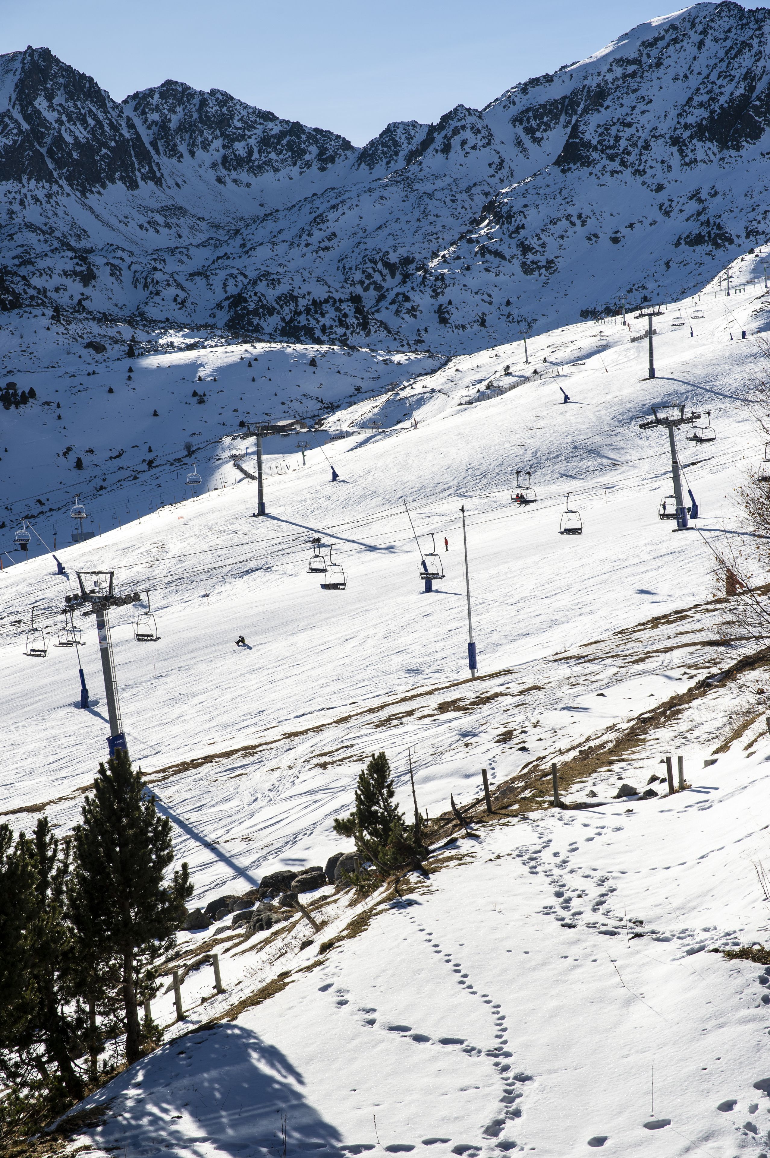 Pista de esquí nevada con remontes y montañas al fondo.