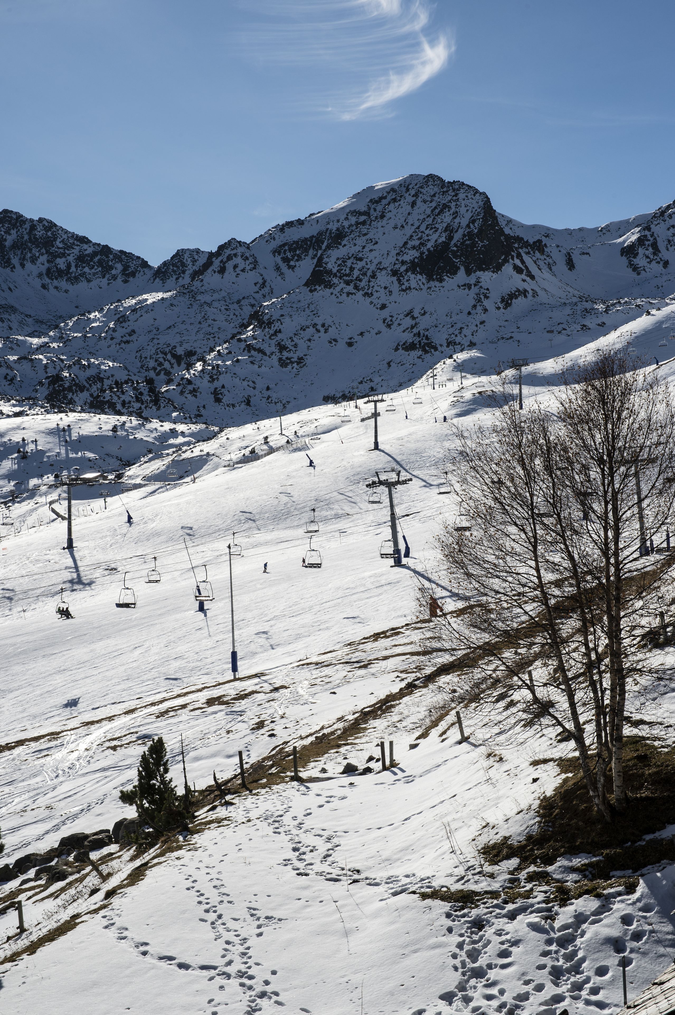 A snow-covered ski slope with ski lifts and a mountain backdrop.