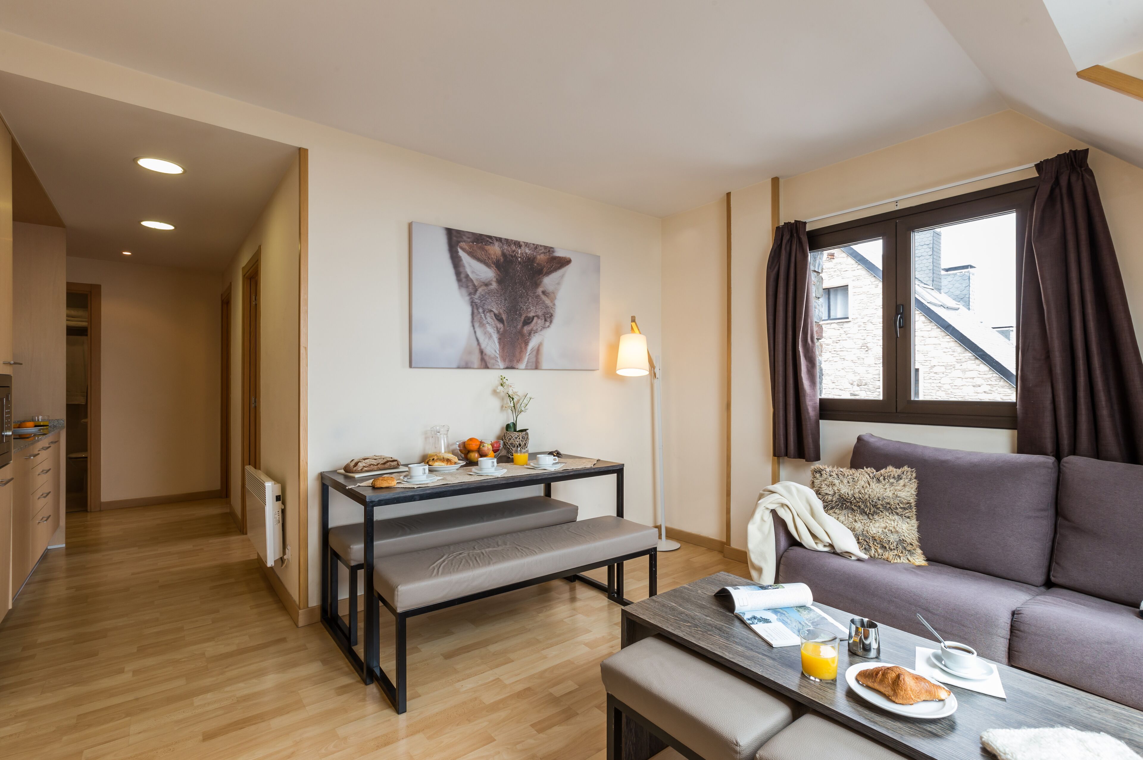 Una sala moderna con un sofá, una mesa de comedor con alimentos para el desayuno, un banco y un cuadro en la pared.