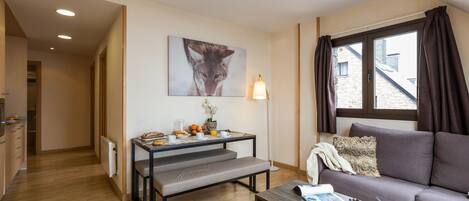 Una sala moderna con un sofá, una mesa de comedor con alimentos para el desayuno, un banco y un cuadro en la pared.