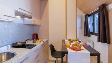 A compact kitchen with a stove, sink, and a dining area with a table set for breakfast.