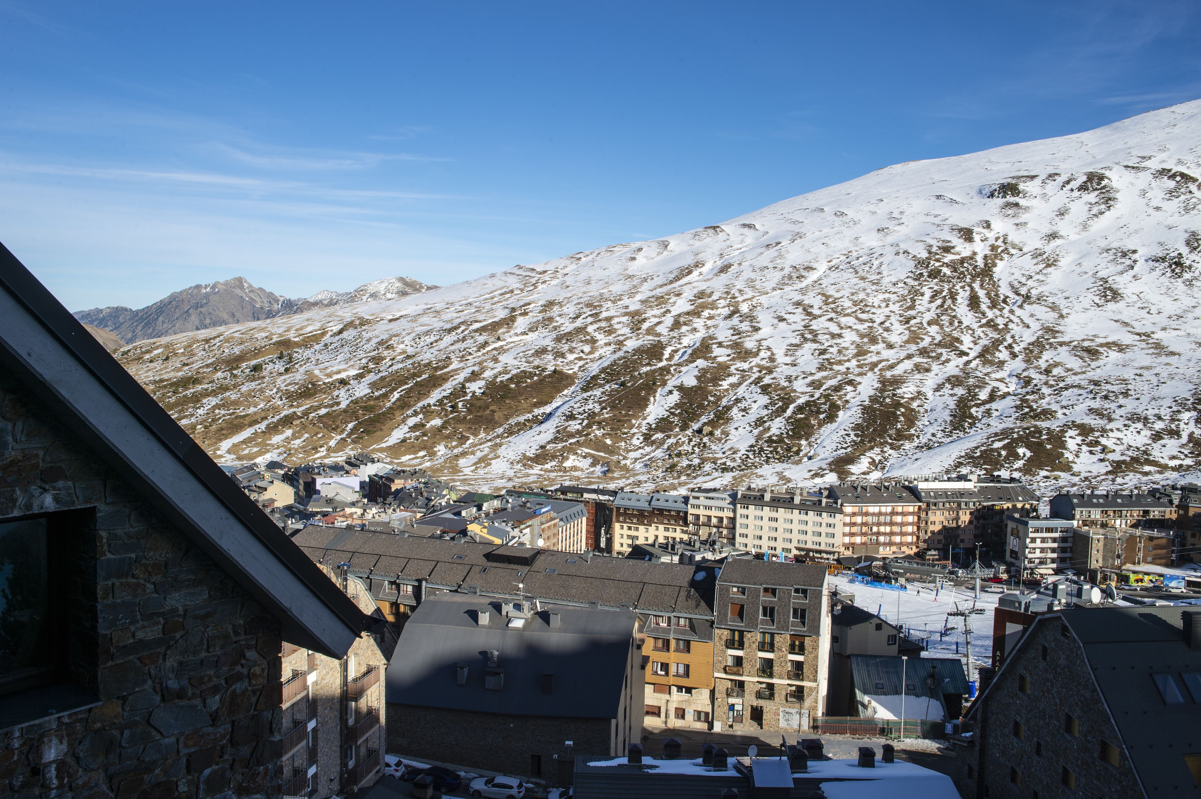 A town with snow-covered mountains in the background and buildings with multiple stories in the foreground.