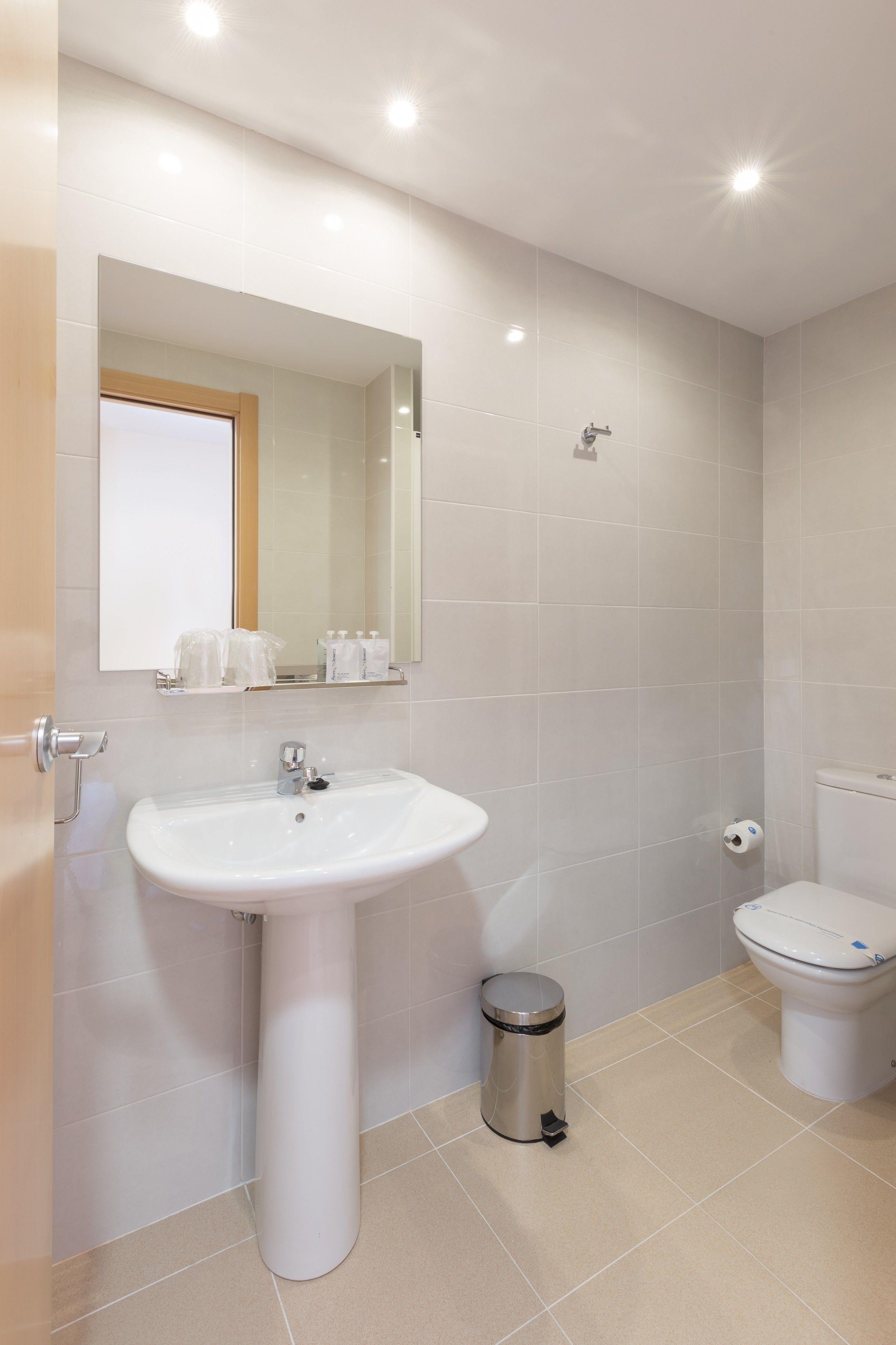 A bathroom with a white sink, mirror, and toilet.