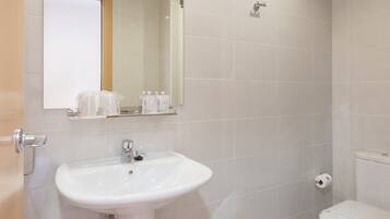 A bathroom with a white sink, mirror, and toilet.