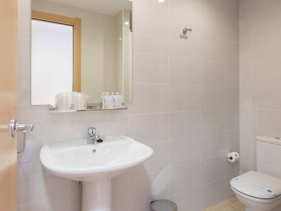 A bathroom with a white sink, mirror, and toilet.