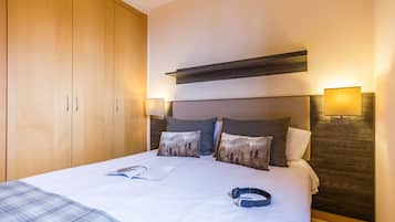 Una habitación de hotel con una cama grande, un armario de madera y dos lámparas fijadas a la pared.