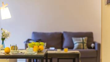 A dining table with a fruit bowl, a cup, and a glass of orange juice.