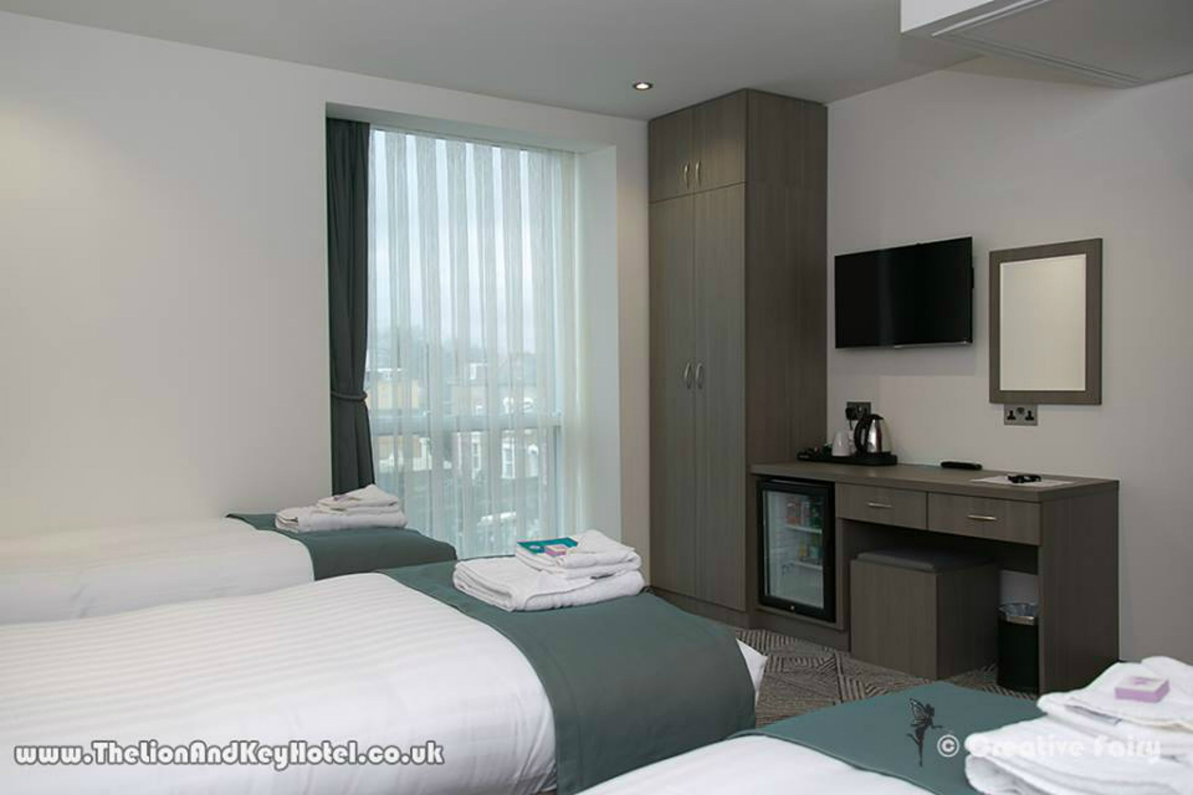 Habitación de hotel con dos camas, un escritorio, televisor y minibar.