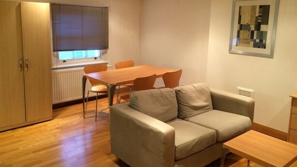 Un espacio habitable compacto con sofá, mesa de comedor y sillas.