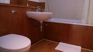 Un baño con tocador de madera, lavamanos blanco, inodoro y bañera.