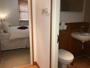 Quarto com uma cama, mesa de cabeceira e janela com persianas.