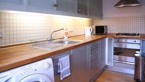 Una cocina moderna con un lavamanos de acero inoxidable, un microondas, una estufa y un horno empotrado.