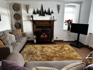 Una sala de estar con chimenea, un sofá, un televisor y decoración en las paredes.