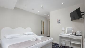 A hotel room with a bed, a desk with a computer, a TV, and a coffee maker.