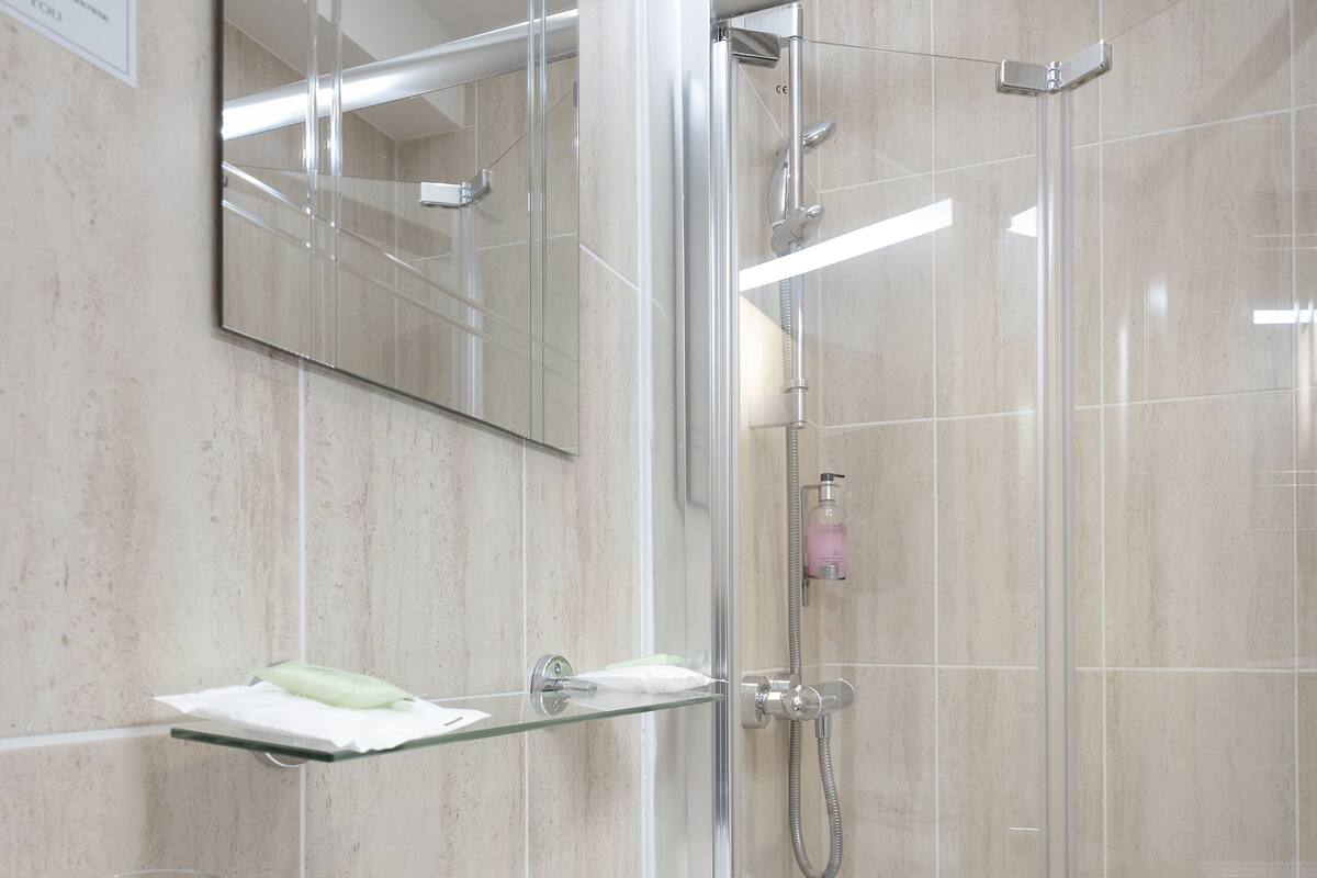 A modern bathroom with a white sink, glass shower enclosure, and a mirror above the sink.