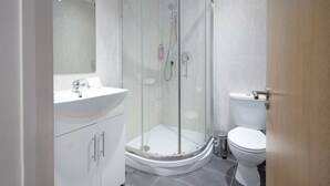 A modern bathroom with a glass-enclosed shower, a white sink, and a toilet.