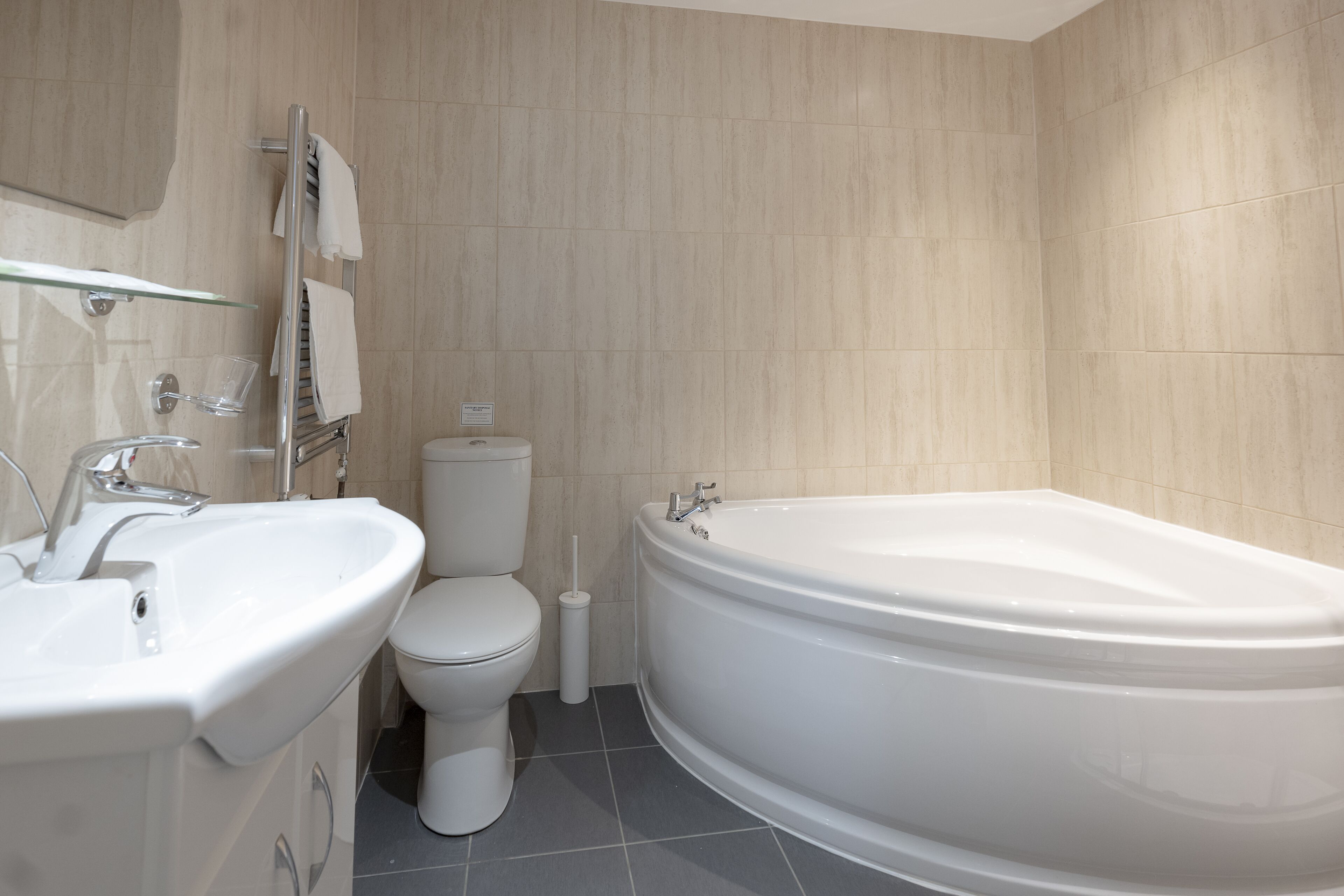 A modern bathroom with a freestanding bathtub, a glass-enclosed sink, and a toilet.
