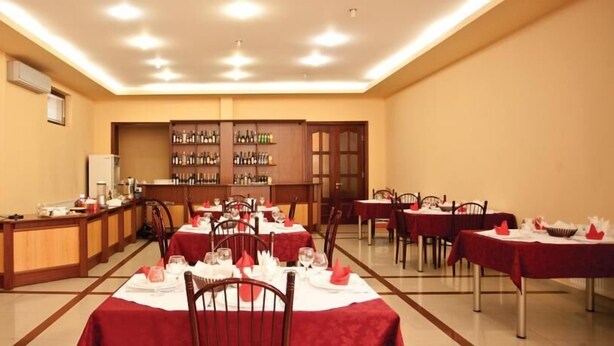 A dining area with tables set for a meal, a bar with a wine selection, and a kitchen area in the background. - Astoria Hotel Tbilisi (Tbilisi)