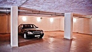 A car parked in a dimly lit, tiled underground parking garage with concrete pillars and exposed pipes. - Astoria Hotel Tbilisi (Tbilisi)