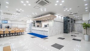 A modern hotel lobby with a reception desk, seating area, and a blue carpet leading to the entrance. - Toyoko Inn Seoul Dongdaemun 1 (Seoul)