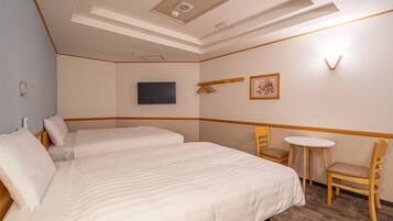 Hotellihuone, jossa on kaksi sänkyä, pieni pöytä ja tuoli.