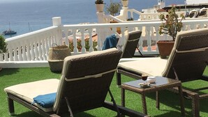 A terrace with wicker lounge chairs, a table, and potted plants. - Apartamentos Alberto (Pajara)