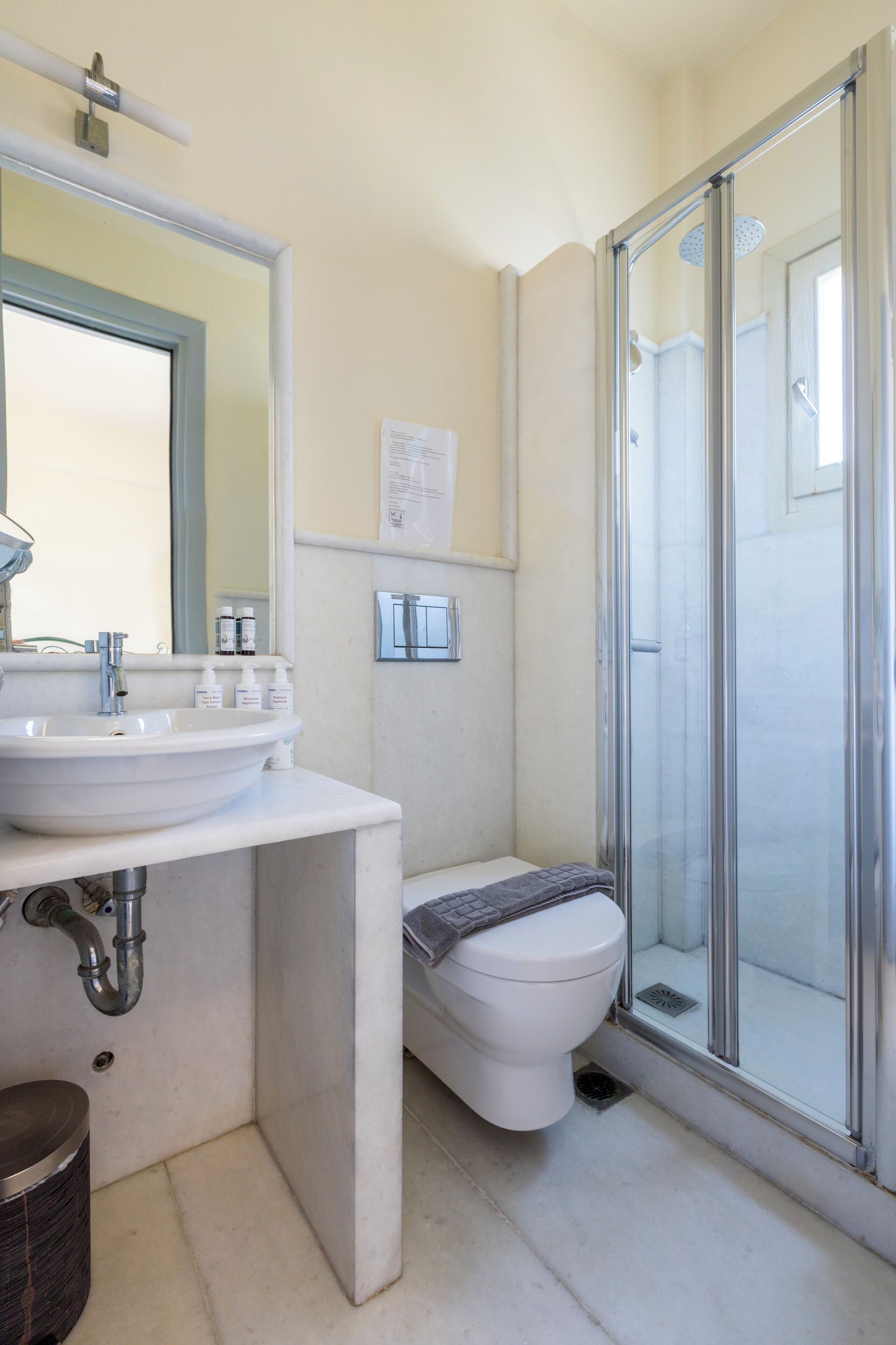 Een badkamer met een wastafel, spiegel, toilet en douchecabine met glazen wanden.