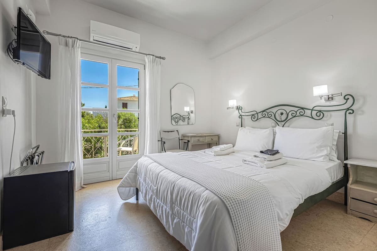 Quarto com cama, escrivaninha, televisão e janela com cortinas.