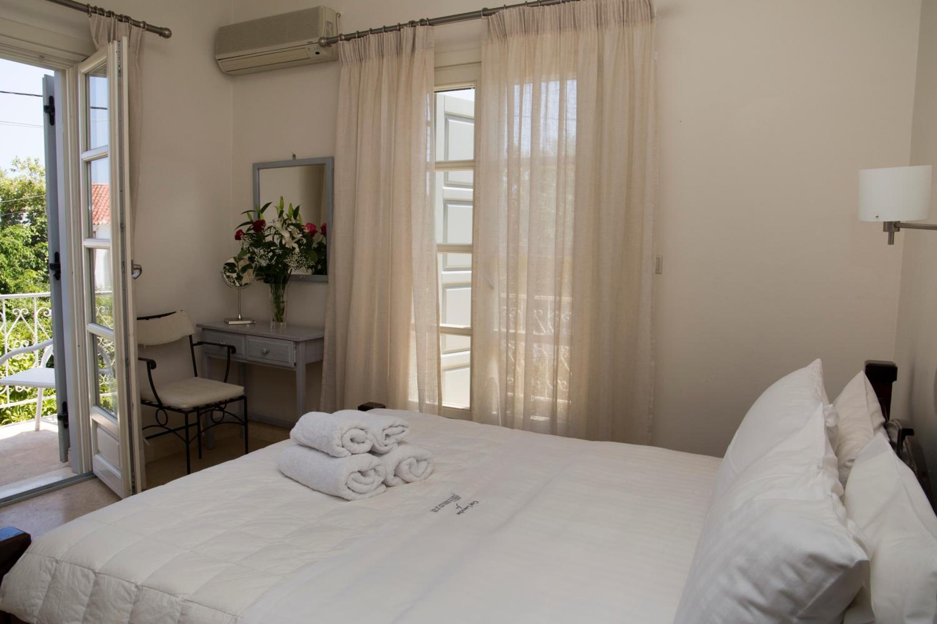 A bedroom with a bed, a desk, a chair, and a window with curtains.