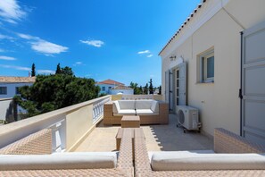 Un balcon Ă©quipĂ© dâun canapĂ©, dâune table et dâun appareil de climatisation.