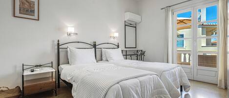 A bedroom with two beds, a bedside table, a wall-mounted air conditioner, and a window with curtains.
