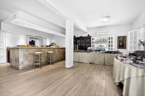A spacious kitchen with a central island, wooden flooring, and a dining area with a table set for a meal. - Mimoza (Spetses)