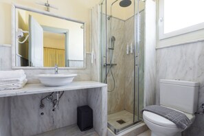 A bathroom with a white sink, mirror, shower, and toilet. - Mimoza (Spetses)
