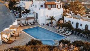 Un hotel con piscina, tumbonas y vistas del paisaje circundante.