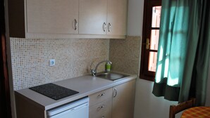 A small kitchen with a sink, a dishwasher, and a window with curtains. - Koula Apartments (Hersonissos)