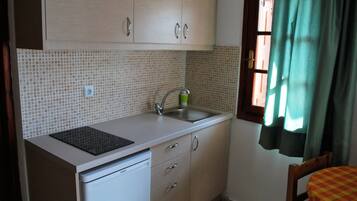 Uma cozinha compacta com pia, lava-louças e janela com cortinas.