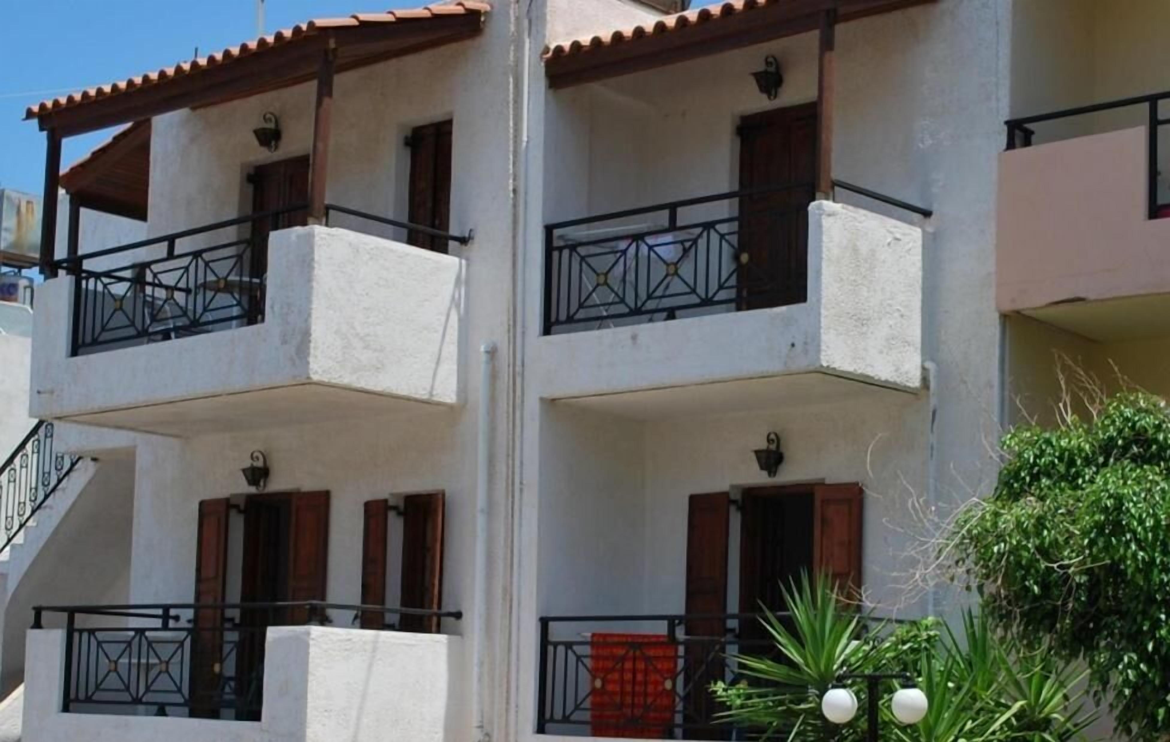 A multi-story building with balconies, staircases, and a red door.