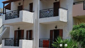 A multi-story building with balconies, staircases, and a red door. - Koula Apartments (Hersonissos)