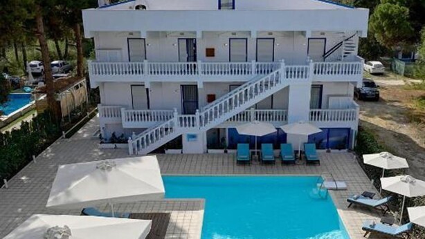 Un hotel con piscina, sillas de descanso y sombrillas.