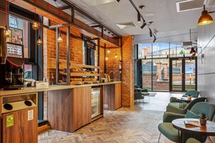 A modern cafe with a wooden counter, a coffee machine, and a recycling bin.