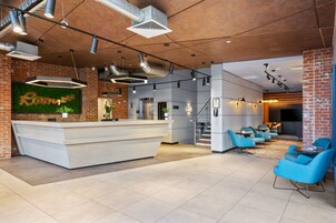 A modern reception area with a white counter, blue seating, and exposed brick walls.