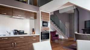 A modern kitchen with wooden cabinets, a microwave, and a built-in oven. There is a staircase leading to an upper level. - Roomzzz Newcastle (Newcastle-upon-Tyne)