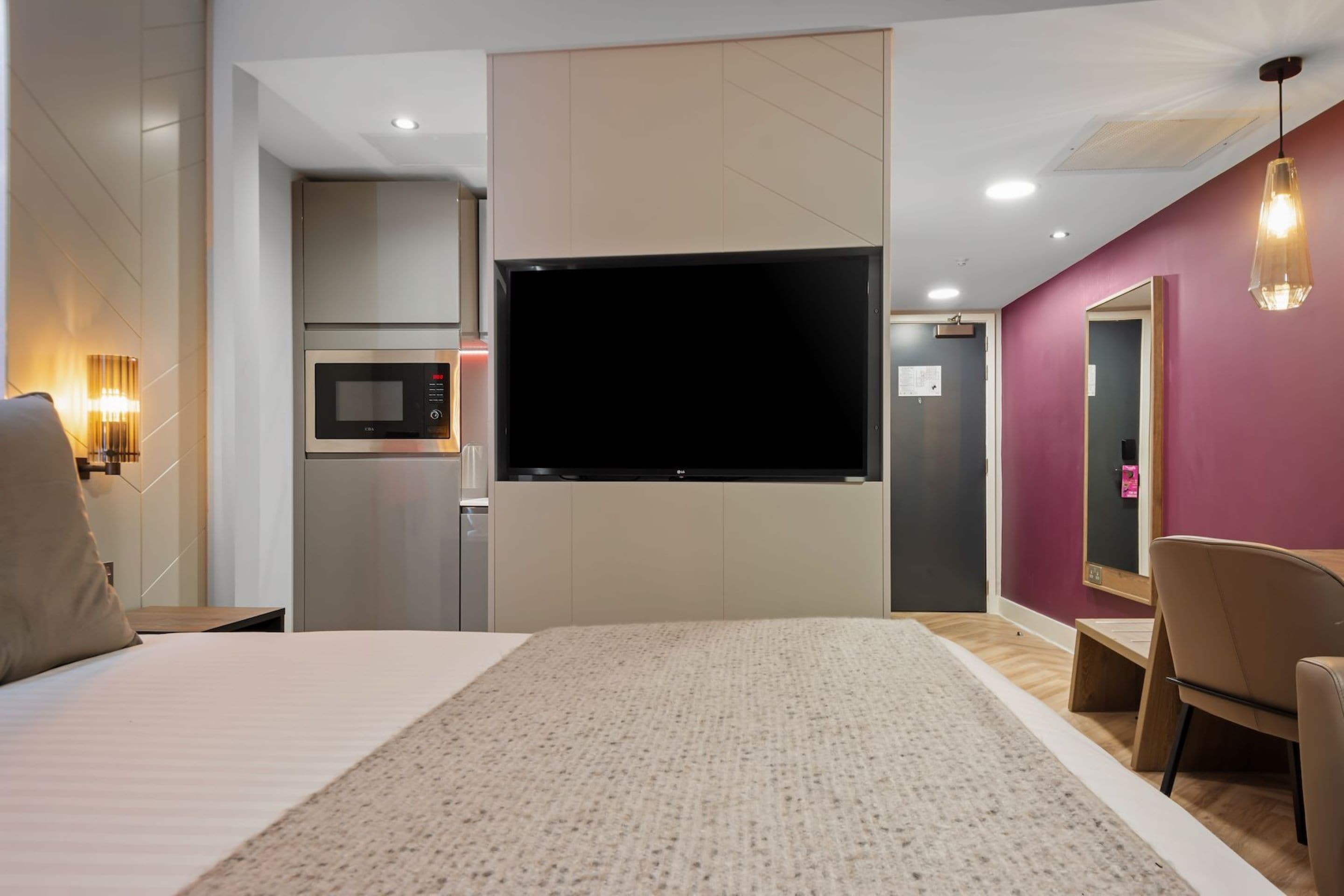 A hotel room with a bed, a TV, a microwave, a desk, and a chair.
